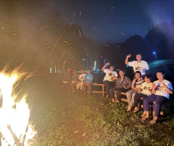 Peserta duduk bersama di dekat api unggun pada malam hari.
