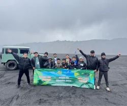 Kelompok peserta berfoto dengan spanduk kegiatan di samping kendaraan jip.