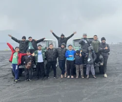 Peserta dan fasilitator berfoto bersama di hamparan pasir pegunungan.