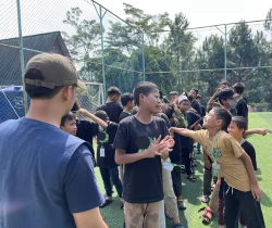 Peserta berinteraksi dalam aktivitas kelompok di lapangan terbuka.